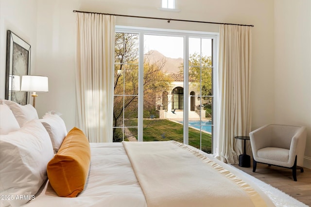 bedroom featuring access to outside, wood finished floors, and a mountain view