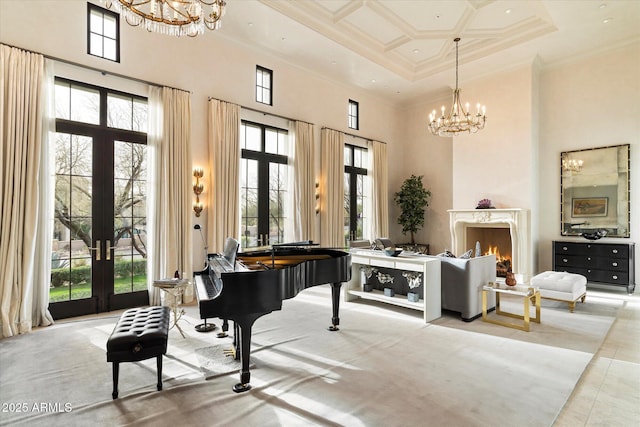 living area with a towering ceiling, a premium fireplace, a notable chandelier, and french doors