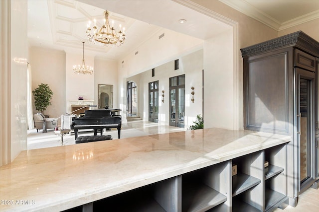 kitchen with a chandelier, crown molding, a towering ceiling, and light stone countertops