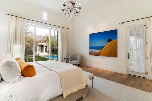 bedroom featuring access to exterior, crown molding, wood finished floors, a chandelier, and baseboards