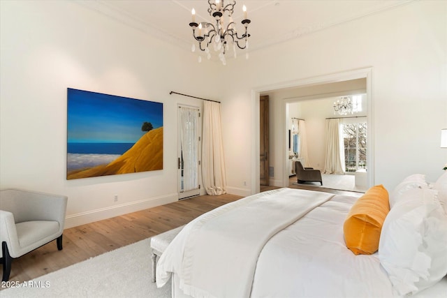 bedroom with crown molding, baseboards, wood finished floors, and a notable chandelier