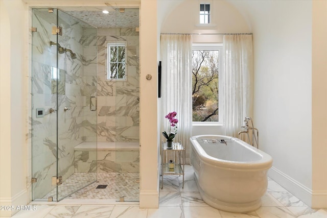 bathroom featuring marble finish floor, a freestanding tub, a marble finish shower, and a healthy amount of sunlight