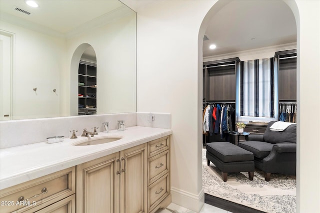 bathroom featuring ornamental molding, a spacious closet, and vanity