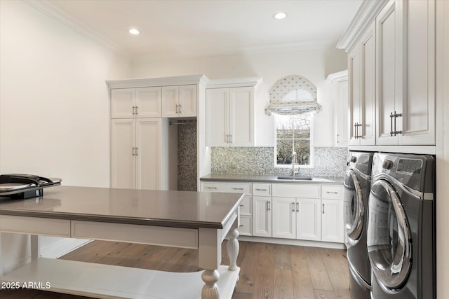 laundry area with a sink, washing machine and dryer, cabinet space, and crown molding