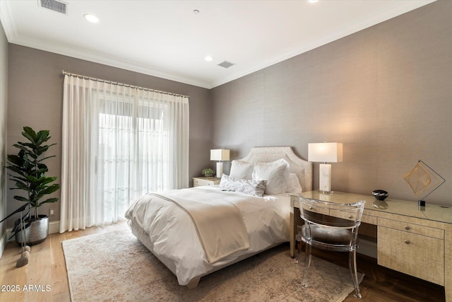 bedroom featuring visible vents, wood finished floors, and ornamental molding