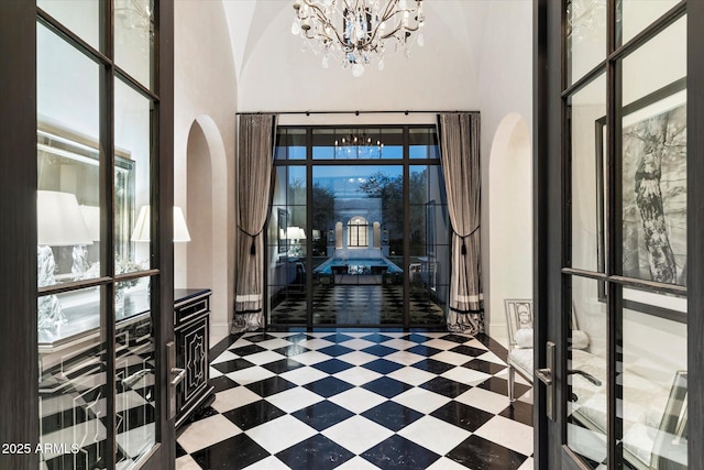 entryway with arched walkways, an inviting chandelier, a high ceiling, and tile patterned floors