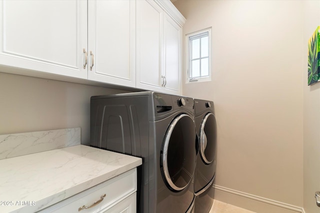 laundry room featuring baseboards, cabinet space, and washing machine and clothes dryer