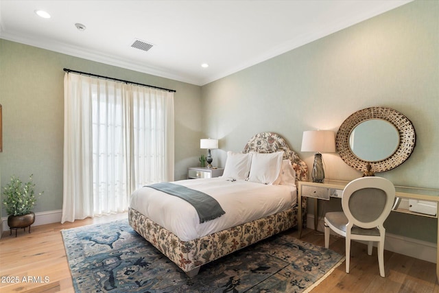 bedroom featuring baseboards, visible vents, wood finished floors, and ornamental molding