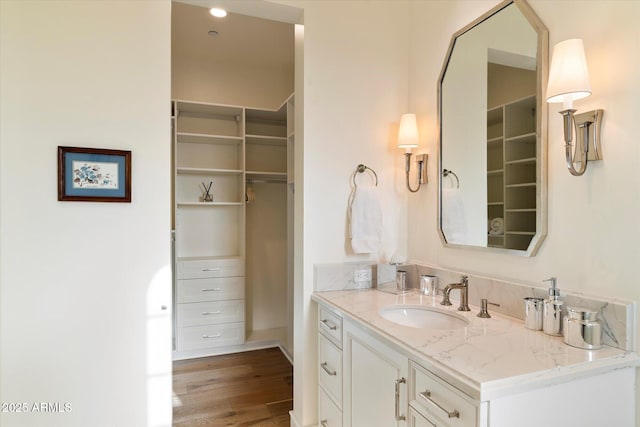 bathroom with vanity, wood finished floors, and a walk in closet