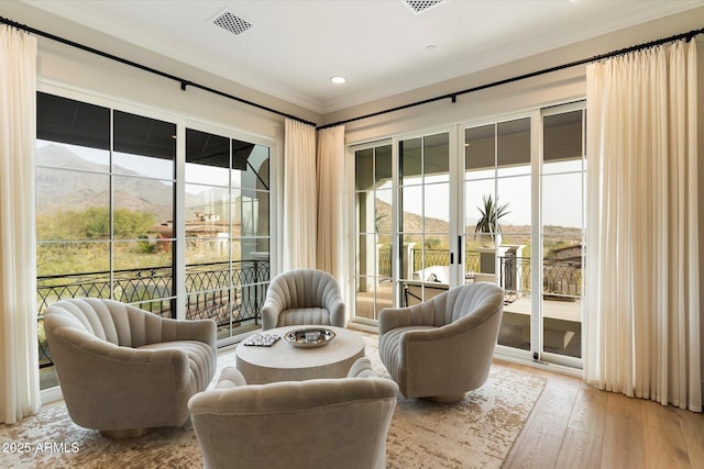 sitting room with wood-type flooring, visible vents, crown molding, and recessed lighting