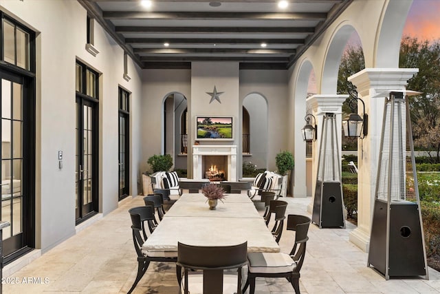 view of patio featuring outdoor dining area and a lit fireplace