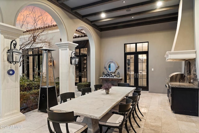 dining room with arched walkways, french doors, decorative columns, and beam ceiling