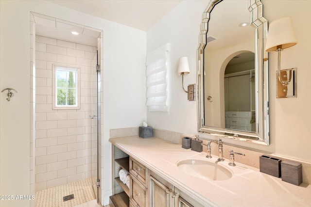 bathroom with recessed lighting, visible vents, tiled shower, and vanity