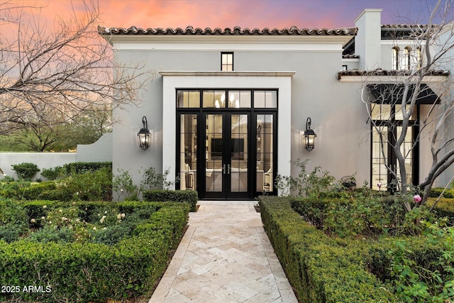 view of exterior entry featuring stucco siding and french doors