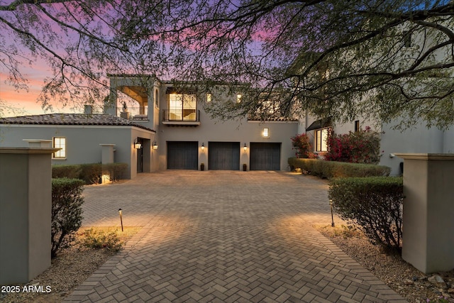 view of front of home featuring a garage, a tiled roof, decorative driveway, and stucco siding