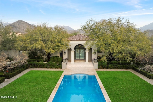 back of house featuring french doors, a tile roof, a lawn, and a mountain view