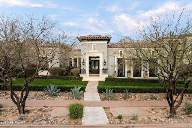 view of front of property with a front yard, french doors, a tiled roof, and stucco siding