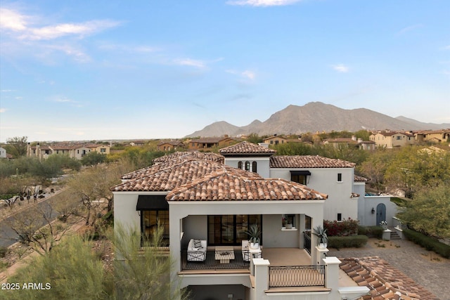 rear view of house featuring a tile roof, a mountain view, and stucco siding