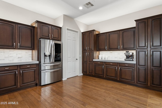 kitchen with dark hardwood / wood-style flooring, dark brown cabinets, tasteful backsplash, and stainless steel refrigerator with ice dispenser