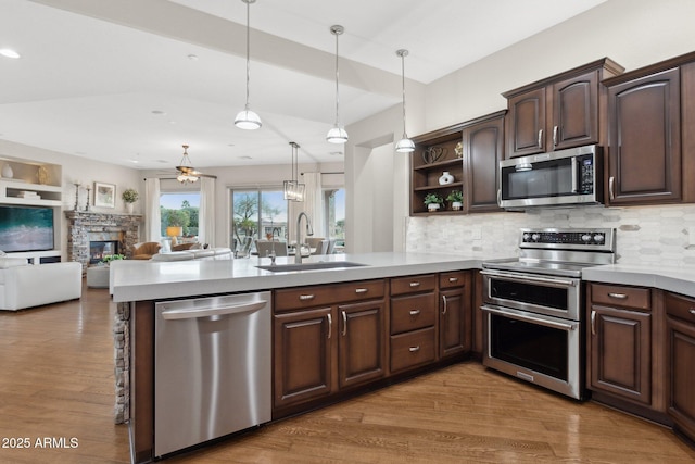 kitchen featuring pendant lighting, sink, appliances with stainless steel finishes, dark brown cabinets, and kitchen peninsula