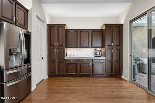 kitchen with dark brown cabinets, stainless steel fridge, and light hardwood / wood-style floors