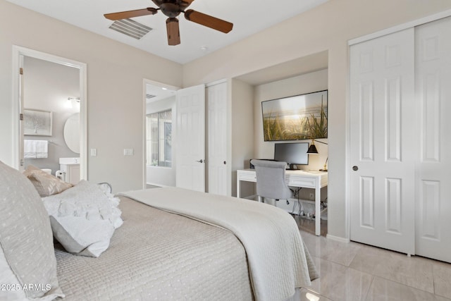 tiled bedroom featuring multiple closets, ceiling fan, and ensuite bath