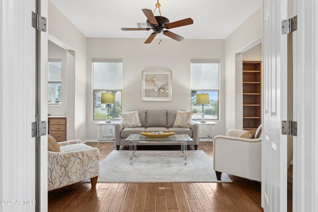 living room with dark wood-type flooring and ceiling fan