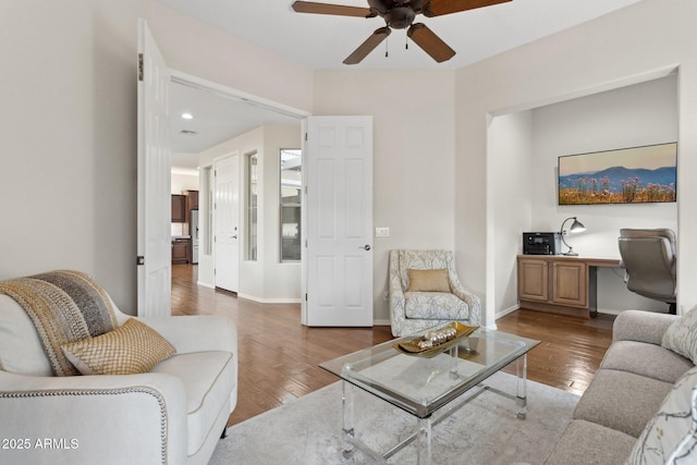 living room featuring ceiling fan, built in desk, and hardwood / wood-style floors