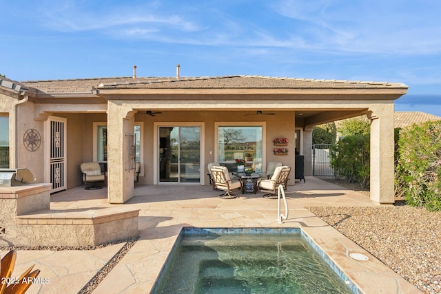 back of property with an outdoor kitchen, ceiling fan, and a patio area