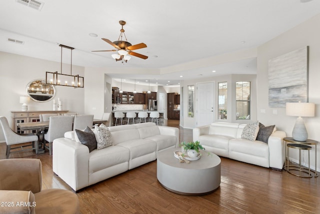 living room featuring hardwood / wood-style flooring and ceiling fan with notable chandelier