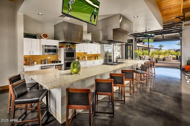 kitchen featuring tasteful backsplash, white cabinetry, island exhaust hood, and stainless steel appliances