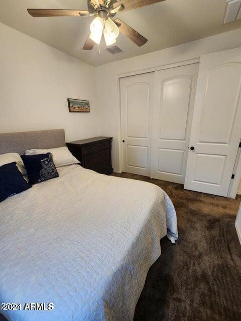 bedroom with ceiling fan, a closet, and dark carpet