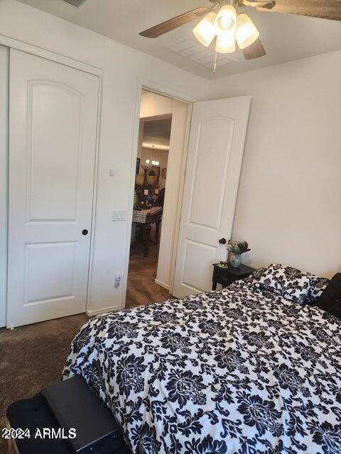 carpeted bedroom with ceiling fan and a closet