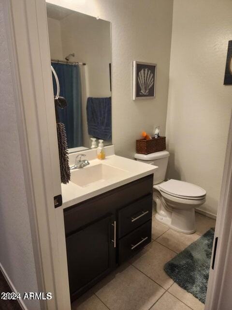 bathroom featuring tile patterned flooring, vanity, toilet, and curtained shower