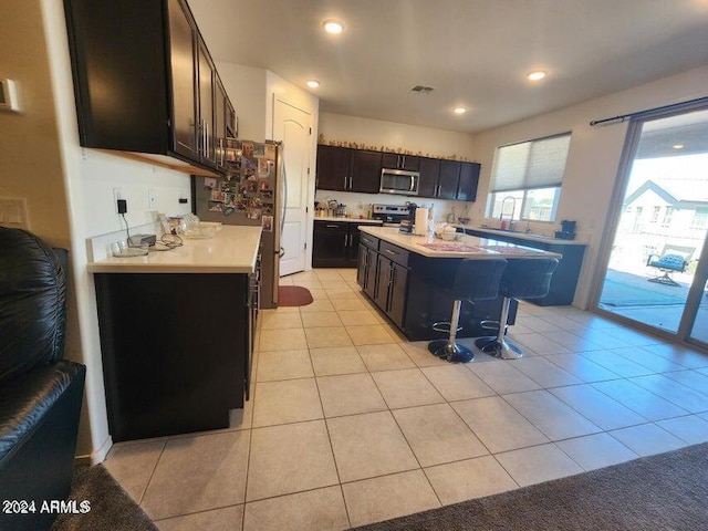 kitchen featuring a breakfast bar area, a kitchen island, light tile patterned floors, and appliances with stainless steel finishes