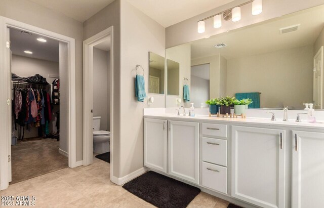 3914 S 58th Ln, Phoenix, AZ 85043 - bathroom featuring toilet, double vanity, a spacious closet, and baseboards