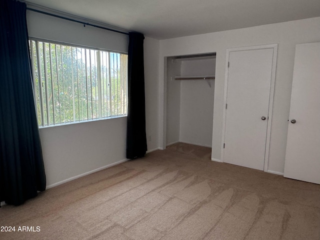 unfurnished bedroom with a closet and light colored carpet