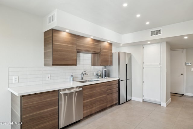 kitchen with light tile patterned floors, appliances with stainless steel finishes, tasteful backsplash, and sink