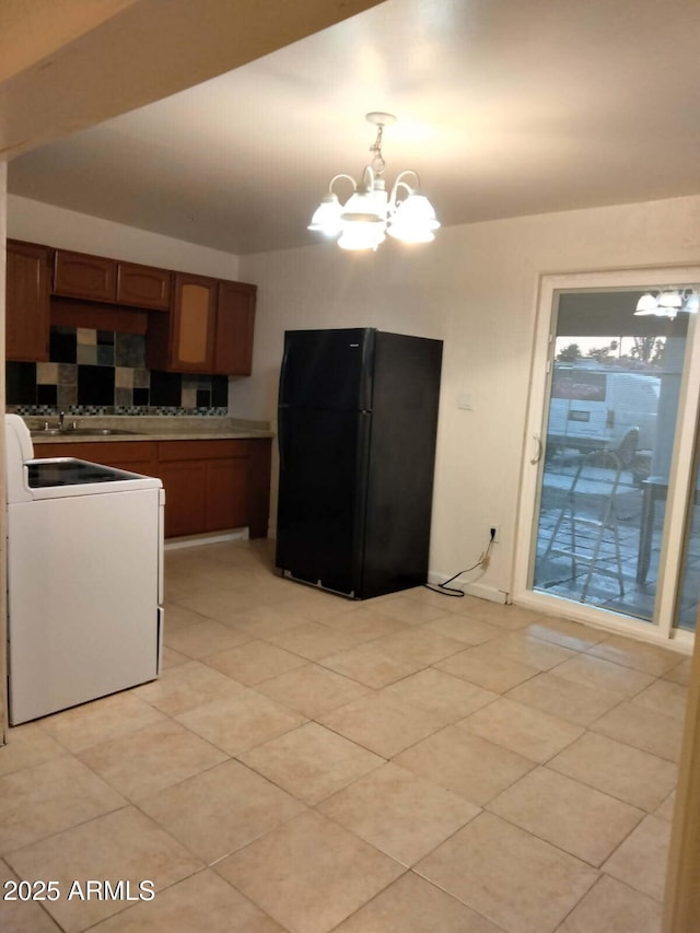 6706 N 54th Dr, Glendale, AZ 85301 - kitchen with freestanding refrigerator, stove, a chandelier, brown cabinetry, and decorative backsplash
