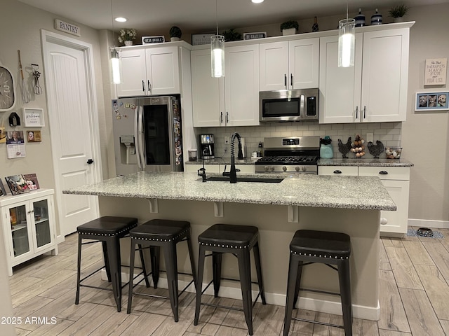 kitchen with decorative backsplash, white cabinetry, appliances with stainless steel finishes, and wood finish floors