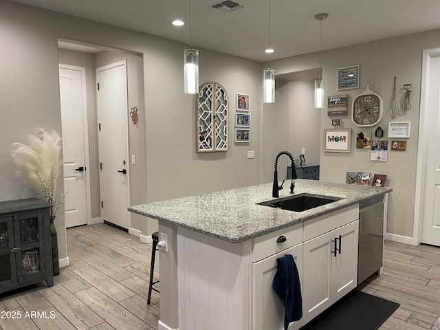 kitchen with light wood finished floors, visible vents, dishwasher, white cabinets, and a sink