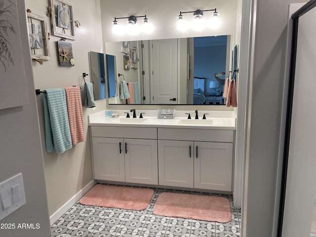 ensuite bathroom featuring a sink, baseboards, ensuite bath, and double vanity