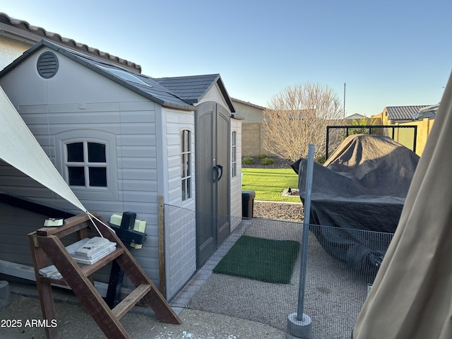 view of home's exterior featuring an outbuilding, a tiled roof, and fence