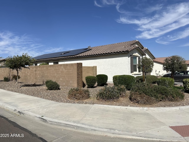 view of property exterior with a tiled roof, stucco siding, and fence