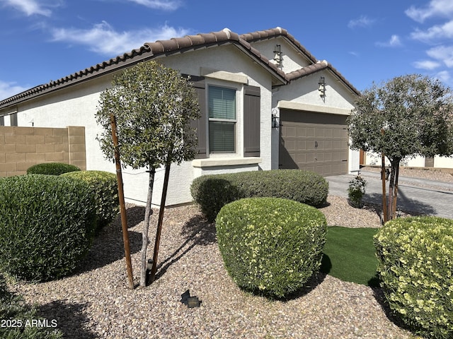 view of front of house featuring fence, an attached garage, stucco siding, concrete driveway, and a tile roof