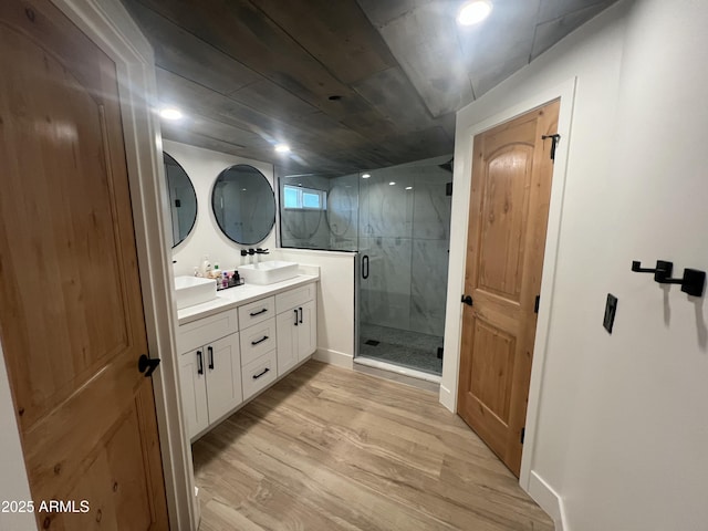 bathroom featuring double vanity, a stall shower, a sink, wood finished floors, and wooden ceiling