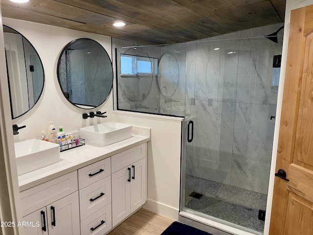 bathroom with double vanity, a stall shower, a sink, and wood finished floors