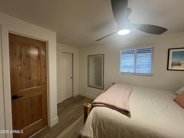 bedroom featuring baseboards, dark wood finished floors, and a ceiling fan