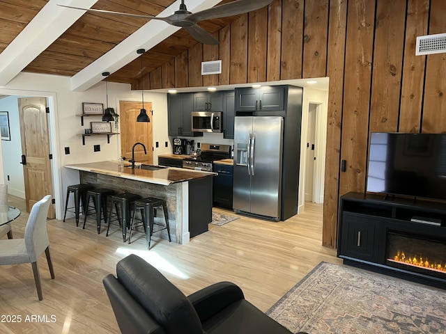 kitchen featuring a breakfast bar area, stainless steel appliances, visible vents, a sink, and a peninsula