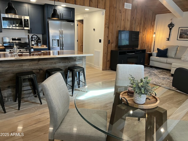 interior space featuring stainless steel appliances, wood walls, visible vents, open floor plan, and light countertops